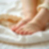 Close-up of delicate newborn barefoot sandals on a soft fabric background